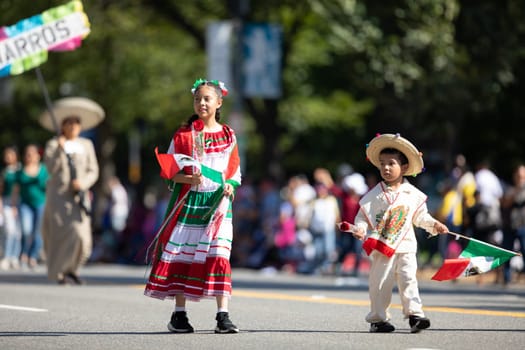 Washington, D.C., USA - September 29, 2018: The Fiesta DC Parade, Boy and girl wearing traditional clothing carrying roses and mexican flags