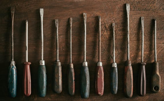 Neat row of old worn vintage screwdrivers with wooden handles on a rustic wood background panorama banner