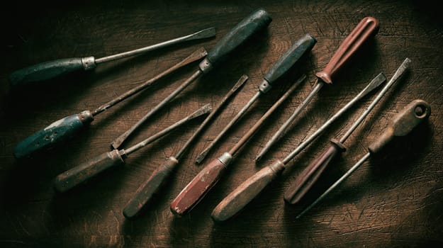 Panorama banner of old worn dirty vintage wooden screwdrivers arranged as a flat lay still life on wood with dark vignette