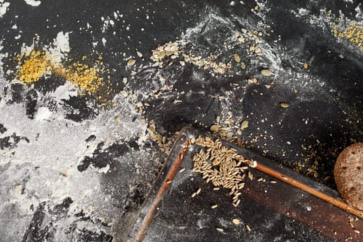 Messy bakery counter with assorted seeds and flour scattered across the surface viewed from above