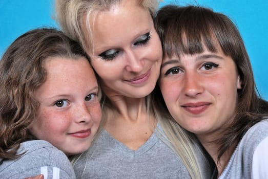 A mother smiles as she receives a kiss on the cheek from her young daughters