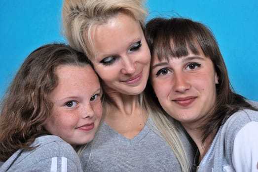 A mother smiles as she receives a kiss on the cheek from her young daughters