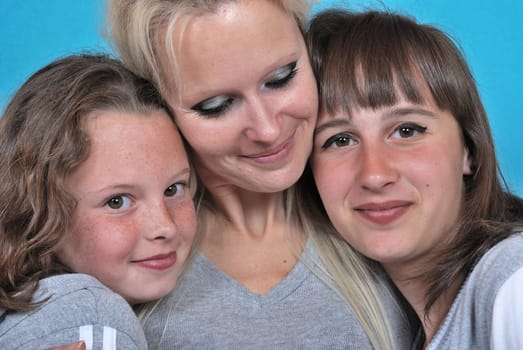A mother smiles as she receives a kiss on the cheek from her young daughters