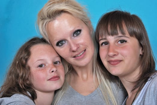 A mother smiles as she receives a kiss on the cheek from her young daughters