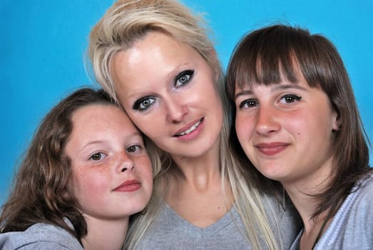 A mother smiles as she receives a kiss on the cheek from her young daughters