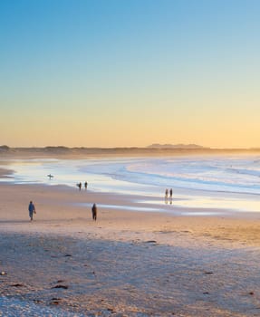 People, surfers walking by the beach at sunset. Baleal, Portugal