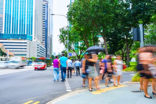 Crowded street of Singapore business district with corporate buildings and traffic on road