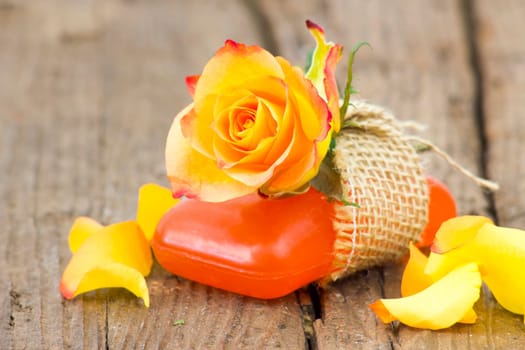 bar of natural soap and rose on wooden background