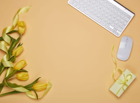 Flowers, gift box, computer keyboard and mouse on a yellow background.Top view with copy space. Design element for romantic greeting card, Women's day, Mother's day, Valentine's day, Female workplace