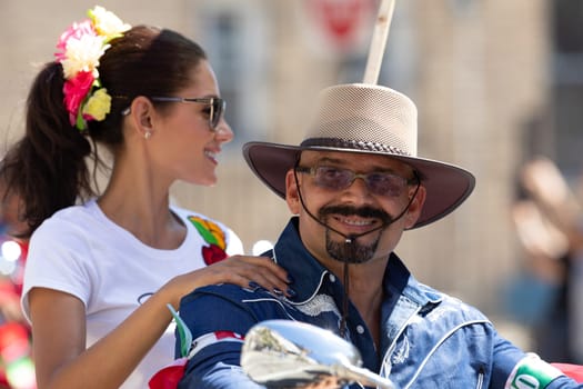 Chicago, Illinois, USA - September 15, 2018: Pilsen Mexican Independence Day Parade, Mexican couple, riding a motorcycle with mexican flags, down the street