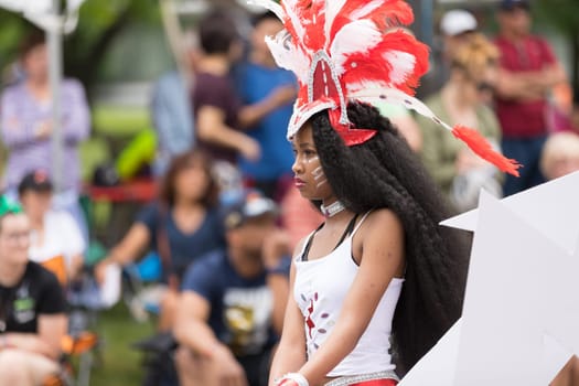 Cleveland, Ohio, USA - June 9, 2018 African american woman wearing a colorful outfit with face paint and feathers on her head At the abstract art festival Parade The Circle