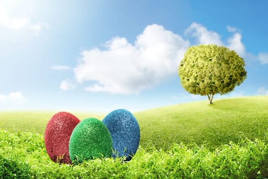 Colorful easter eggs on the green grass with tree and blue sky background. Happy Easter