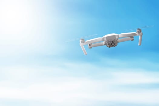 White drone with camera flying over blue sky background