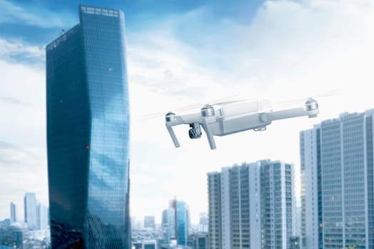 White drone with camera flying over the city with skyscrapers and blue sky background