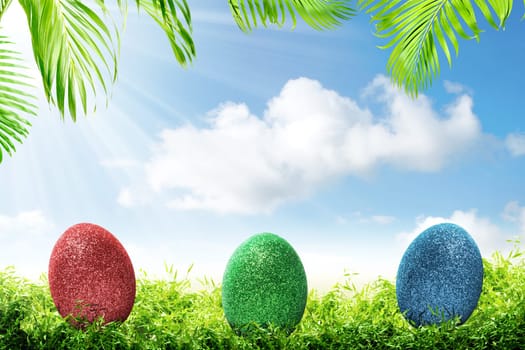 Colorful easter eggs on the green grass with palm branches and blue sky background. Happy Easter