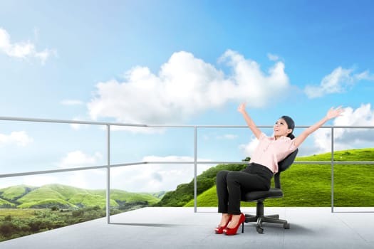 Pretty asian business woman sitting on the chair and relaxing on the terrace with green landscapes view and blue sky background