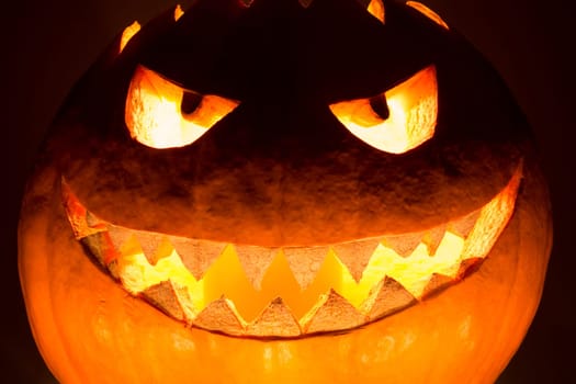 Spooky helloween symbol has glowing closeup mad face and smiling with sharp teeth and bad look. Black orange nightmare of October 31st.