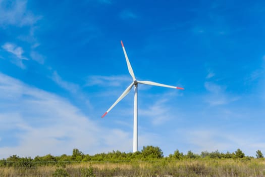 Sustainability by windmills turbines preventing climate change with regenerative clean green nature energy. Windy blue sky with clouds