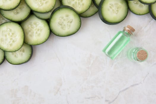 Cucumber slices and small bottle of cucumber extract flat lay with copy space.