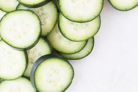 Cucumber slices on marble, flat lay with copy space
