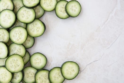 Cucumber slices on marble, flat lay with copy space