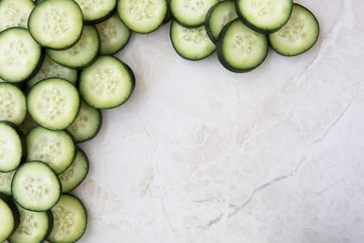 Cucumber slices on marble, flat lay with copy space