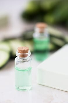 Cucumber extract in small bottle with bar of soap and cucumber slices.