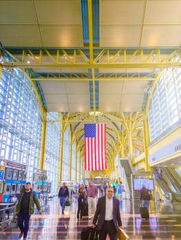 Washington D.C., USA, November 2016  Tourists and businessmen walking inside the Ronald Reagan airport of Washington D.C. before taking their flight. Large American flag hanging from the ceiling