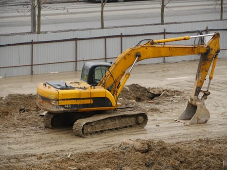 yellow excavator at a construction site side view