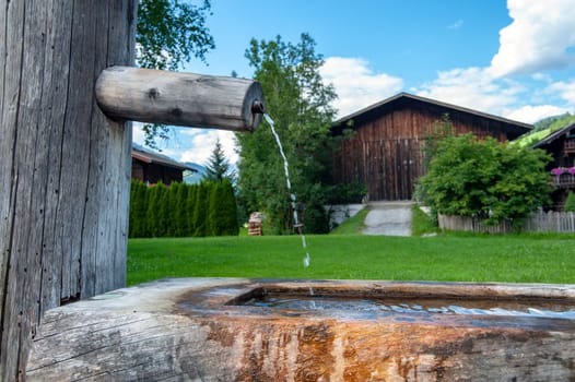 old wooden well in front of summer village background