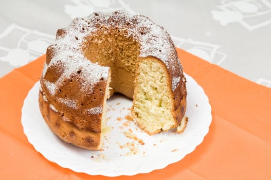 Homemade ring cake dusted with icing sugar on white plate