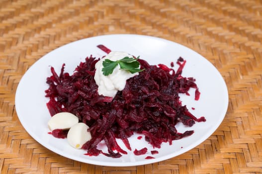 Grated beets with garlic in a plate on the table close-up