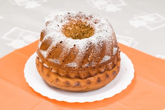 Homemade ring cake dusted with icing sugar on white plate