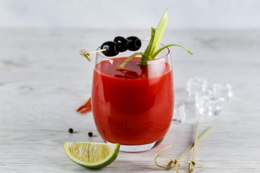 Cocktail Bloody Mary with lime and celery and olives on a skewer