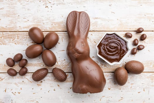 Delicious chocolate Easter bunny, eggs and sweets on rustic background