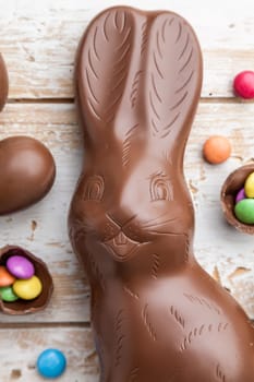 Delicious chocolate Easter bunny, eggs and sweets on rustic background