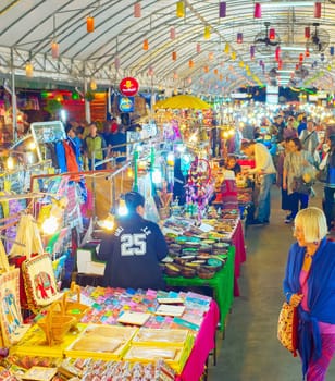 CHIAG MAI, THAILAND - JANUARY 11, 2017: Crowd of tourists walking among colorful illuminated stands of asian night souvenir market