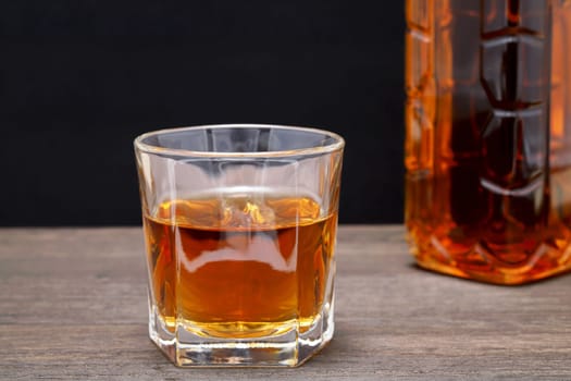 glass cup and bottle of whiskey on a old wooden table