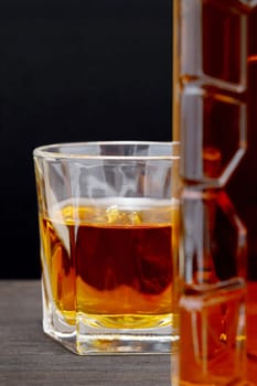 glass cup and bottle of whiskey on a old wooden table