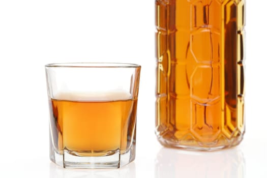 Glass cup and bottle of whiskey on white background