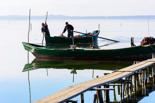 Bruncuteula, Sant'Antioco, Italy - January 28, 2016: Fishermen with their ancient boats, fall at dawn, landscape of the lagoon of Sant'Antioco in south west Sardinia.