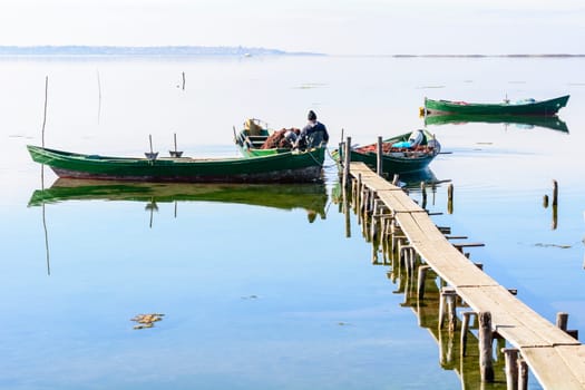 Bruncuteula, Sant'Antioco, Italy - January 28, 2016: Fishermen with their ancient boats, fall at dawn, landscape of the lagoon of Sant'Antioco in south west Sardinia.