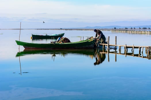 Bruncuteula, Sant'Antioco, Italy - January 28, 2016: Fishermen with their ancient boats, fall at dawn, landscape of the lagoon of Sant'Antioco in south west Sardinia.