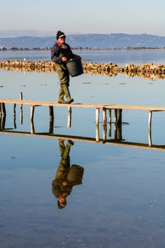 Bruncuteula, Sant'Antioco, Italy - January 28, 2016: Fishermen with their ancient boats, fall at dawn, landscape of the lagoon of Sant'Antioco in south west Sardinia.