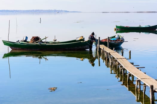 Bruncuteula, Sant'Antioco, Italy - January 28, 2016: Fishermen with their ancient boats, fall at dawn, landscape of the lagoon of Sant'Antioco in south west Sardinia.