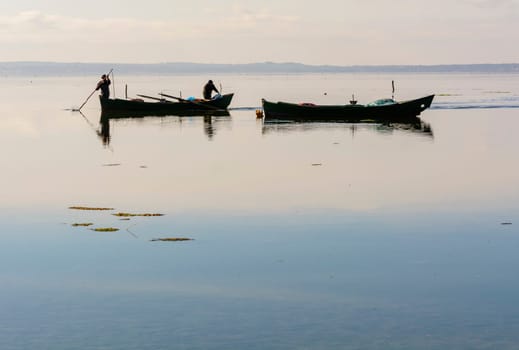 Bruncuteula, Sant'Antioco, Italy - January 28, 2016: Fishermen with their ancient boats, fall at dawn, landscape of the lagoon of Sant'Antioco in south west Sardinia.