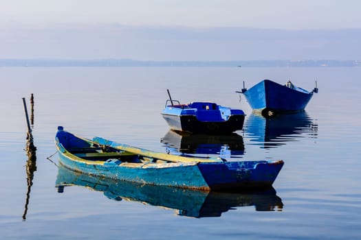 Old wooden fishing boats with bright colors at dawn on the lake. Landscape of lagoon in Sardinia south west.