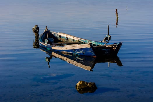 Old wooden fishing boats with bright colors at dawn on the lake. Landscape of lagoon in Sardinia south west.