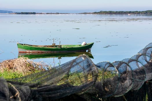 Moorhen in the calm lagoon at dawn. In the foreground the details of an old wooden fishing boat.