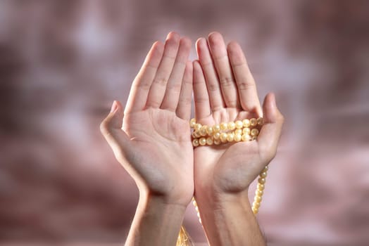Muslim hands praying with prayer beads over blurry background